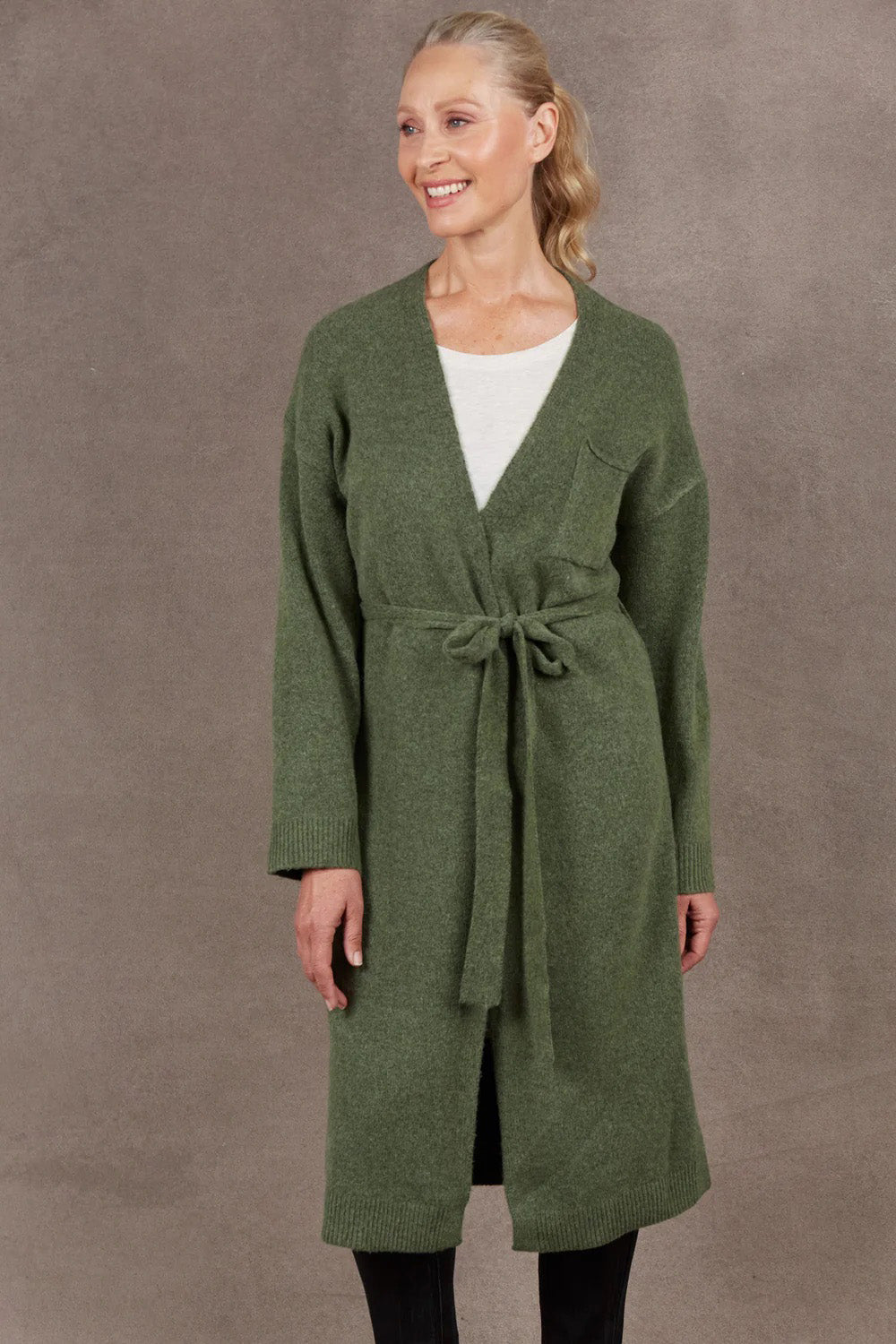 A model wearing the Paarl Longline Cardigan in colour Moss (Green), from the front, cropped image