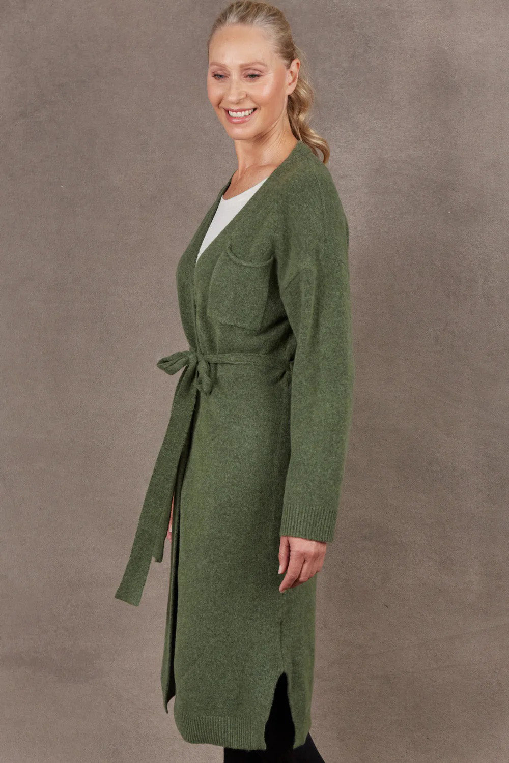A model wearing the Paarl Longline Cardigan in colour Moss (Green), from the front, cropped image