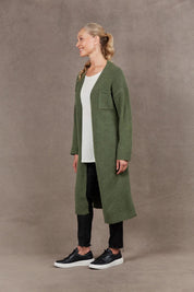 A model wearing the Paarl Longline Cardigan in colour Moss (Green), from the front, showing the whole outfit