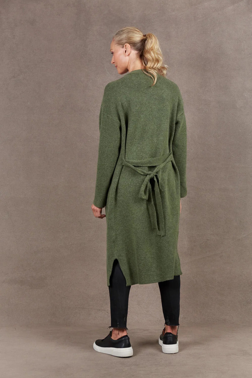 A model wearing the Paarl Longline Cardigan in colour Moss (Green), from the front, showing the whole outfit