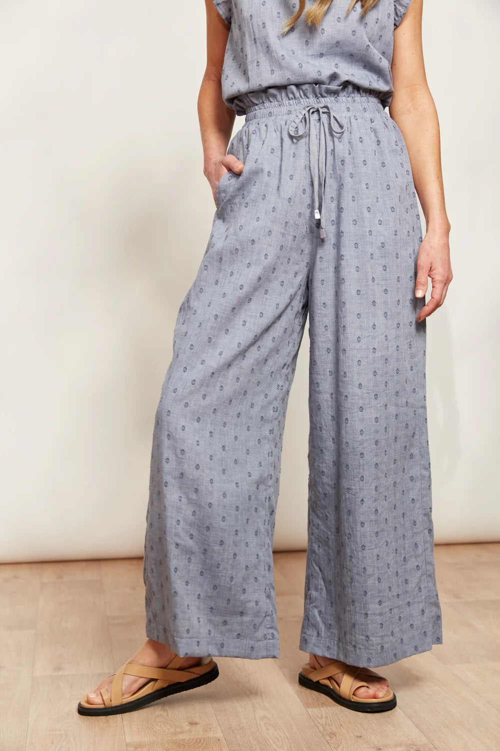 A model wearing the Zephyr Pant in colour Nevada (Blue), from the front, showing the whole outfit