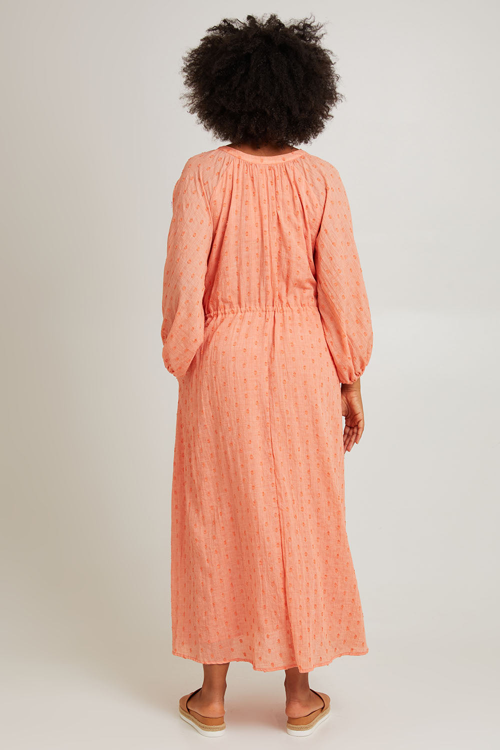 Model Olivia wearing size S of the Zephyr Maxi Dress in colour Papaya, from the back
