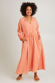 Model Olivia wearing size S of the Zephyr Maxi Dress in colour Papaya, from the front, showing the whole outfit