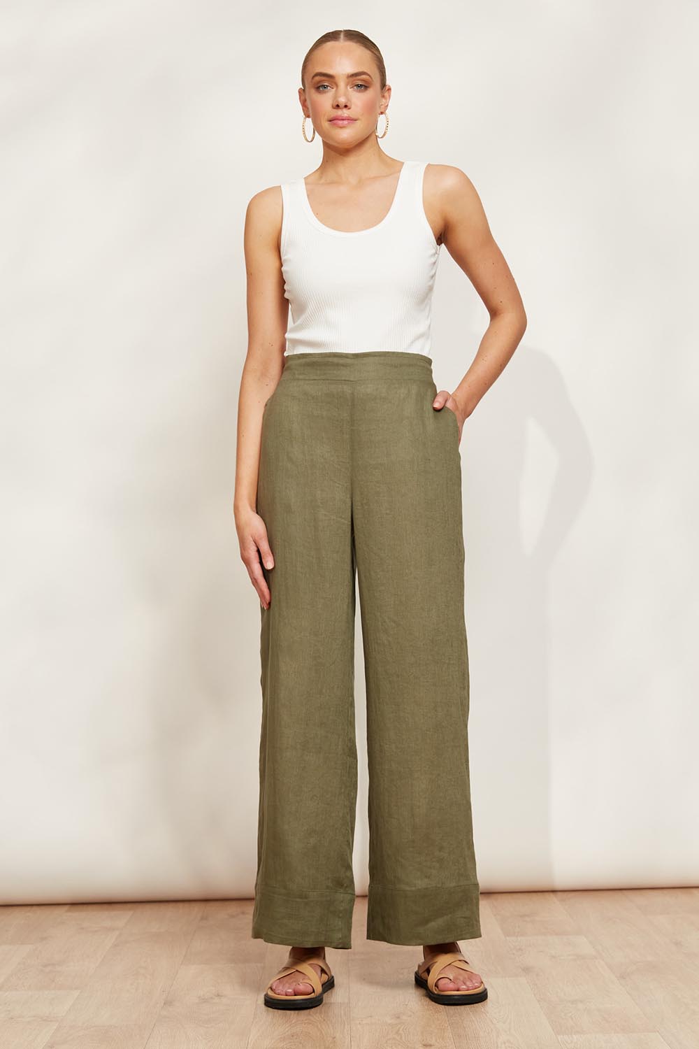 A model wearing the Studio Linen Pant in colour Khaki (Green), from the front, showing the whole outfit
