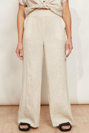 A model wearing the Studio Linen Pant in colour Tusk, from the front, cropped image