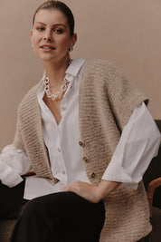 A model wearing the Folie Button Vest in colour Oat, from the front, showing the whole outfit