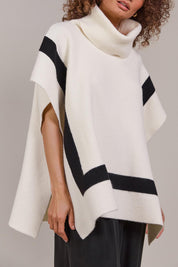 A model wearing the Avino Poncho in colour Ecru, from the front, cropped image