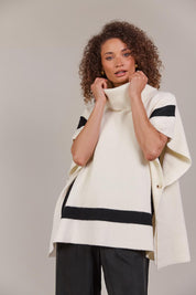 A model wearing the Avino Poncho in colour Ecru, from the front, cropped image