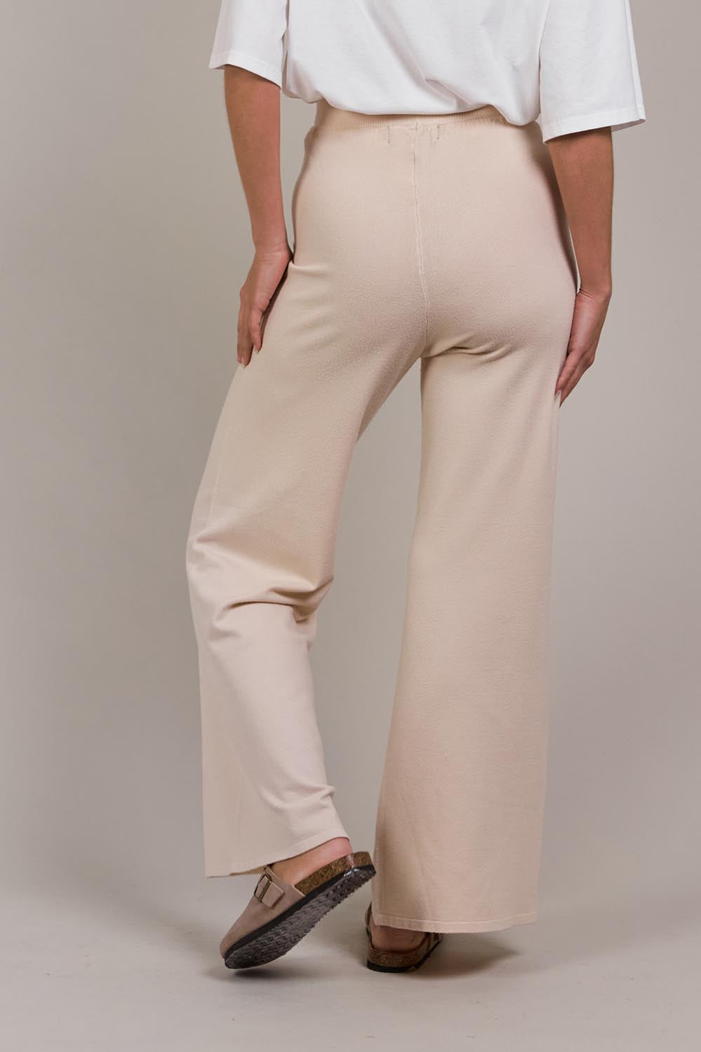 A model wearing the Palmer Knit Pant in colour Ecru, from the back