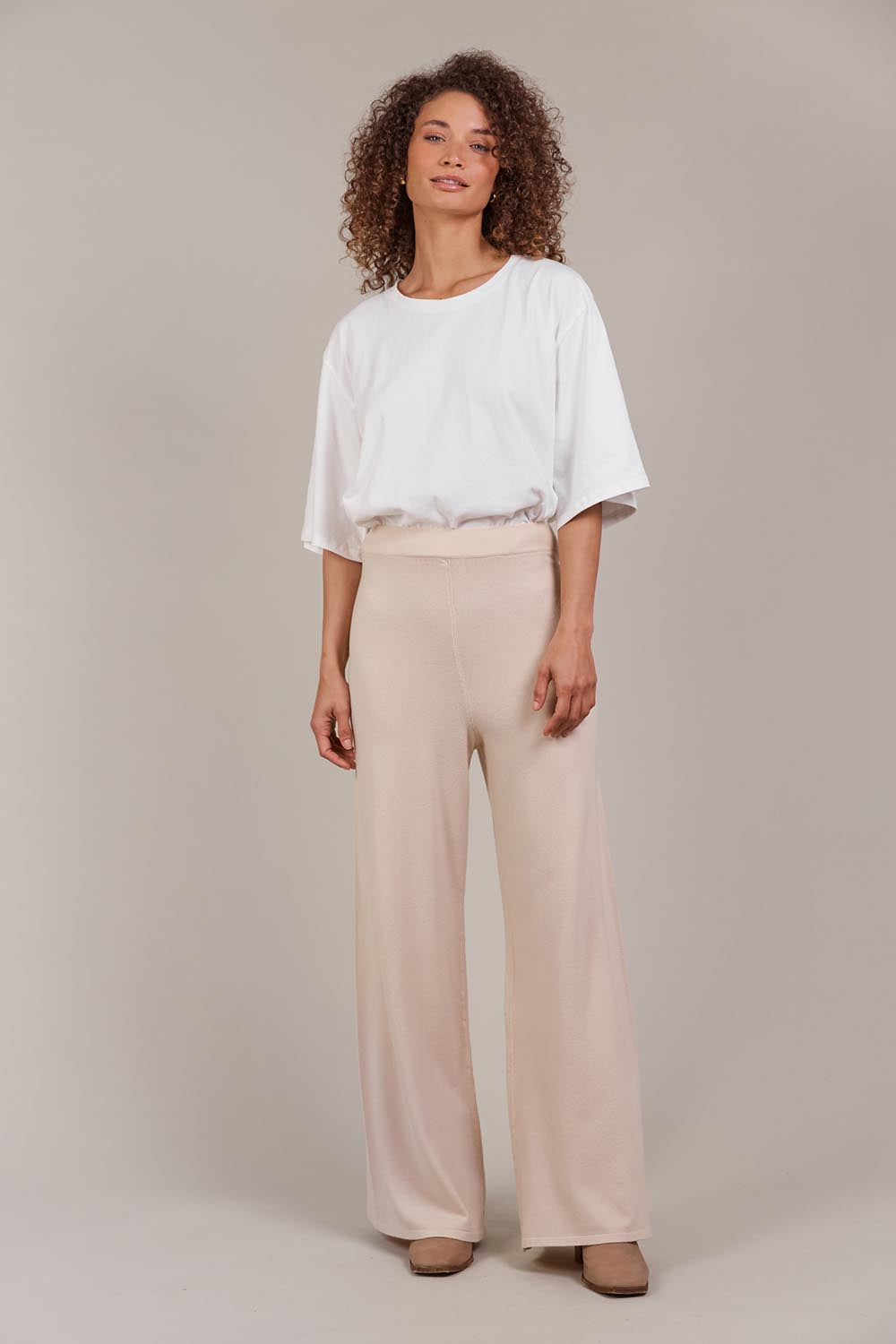 A model wearing the Palmer Knit Pant in colour Ecru, from the front, showing the whole outfit