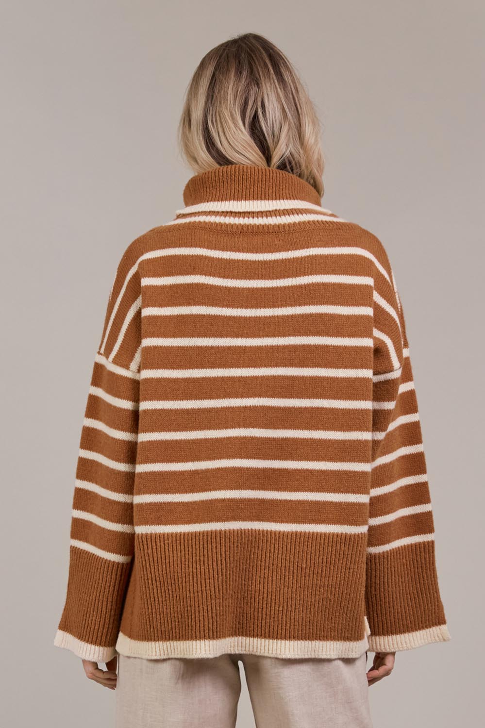 A model wearing the Katana Roll Neck Knit in colour Hazel, from the back