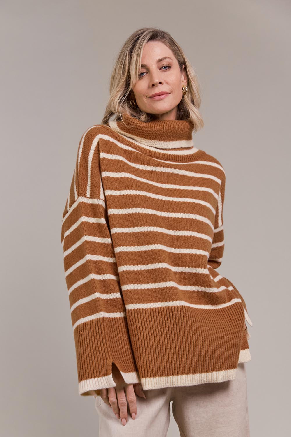 A model wearing the Katana Roll Neck Knit in colour Hazel, from the front, cropped image