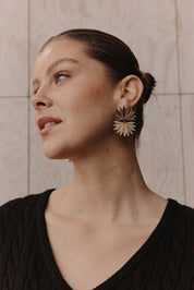A model wearing the Laax Fan Earring in colour Gold (Metallics), from the front, showing the whole outfit