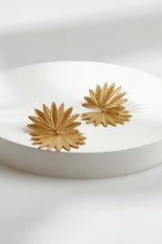 A model wearing the Laax Fan Earring in colour Gold (Metallics), from the front, showing the whole outfit