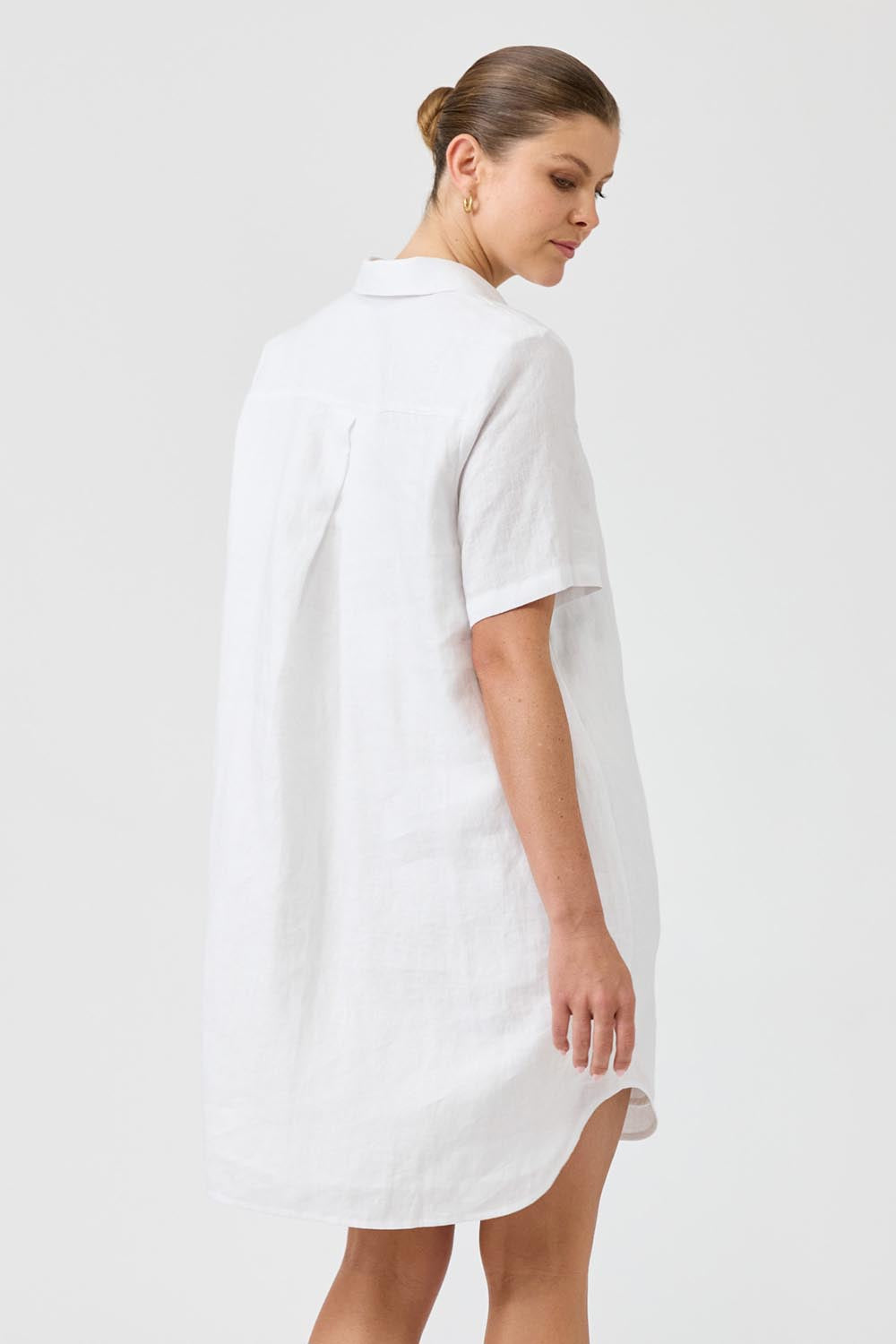 A model wearing the Studio Linen Short Shirt Dress in colour White (White), from the back