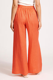 A model wearing the Miranar Linen Palazzo Pant in colour Coral (Red), from the back