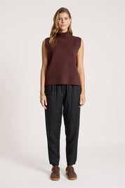 A model wearing the Zala Knit Vest in colour Mahogany (Red), from the front, showing the whole outfit