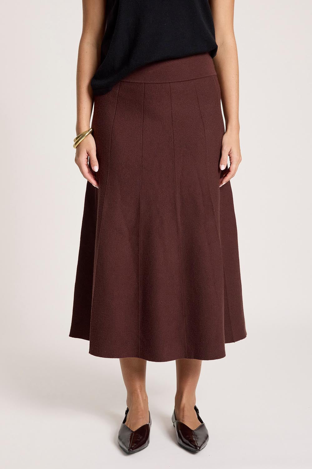 A model wearing the Zala Knit Skirt in colour Mahogany (Red), from the front, cropped image
