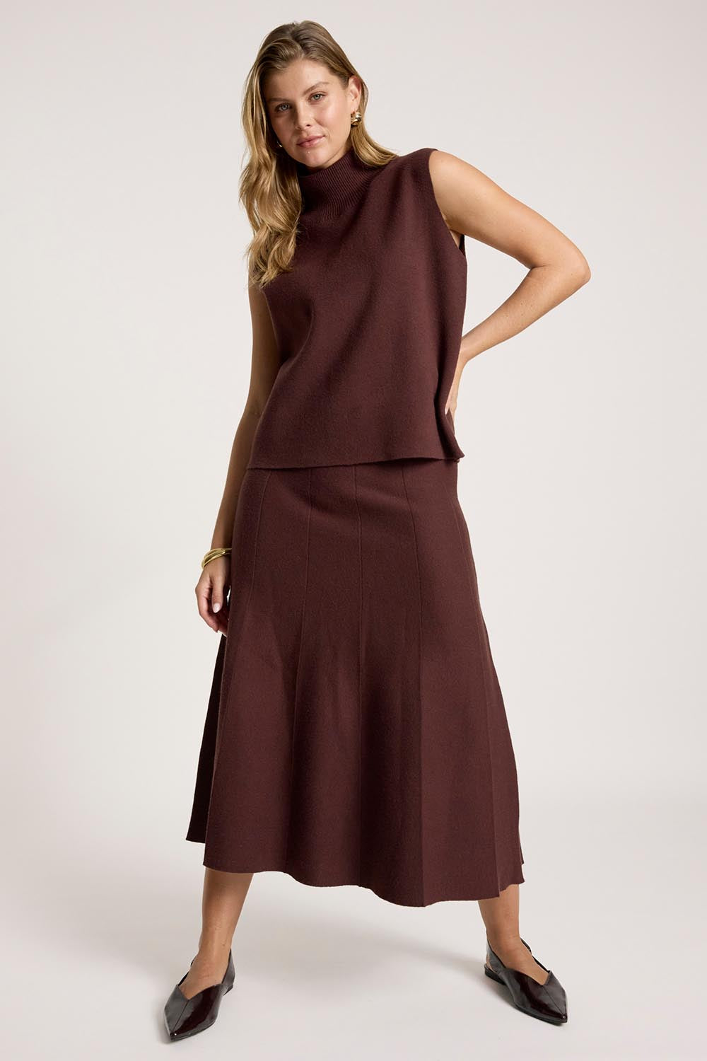 A model wearing the Zala Knit Skirt in colour Mahogany (Red), from the front, showing the whole outfit