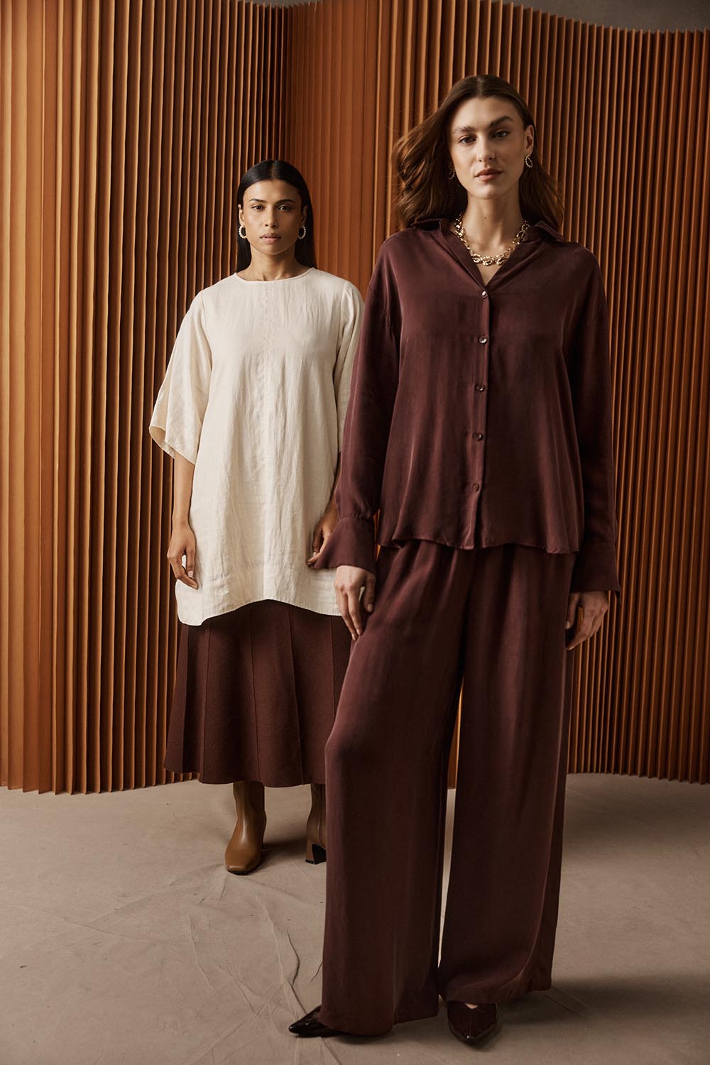 A model wearing the Calista Pant in colour Mahogany (Red), from the front, showing the whole outfit