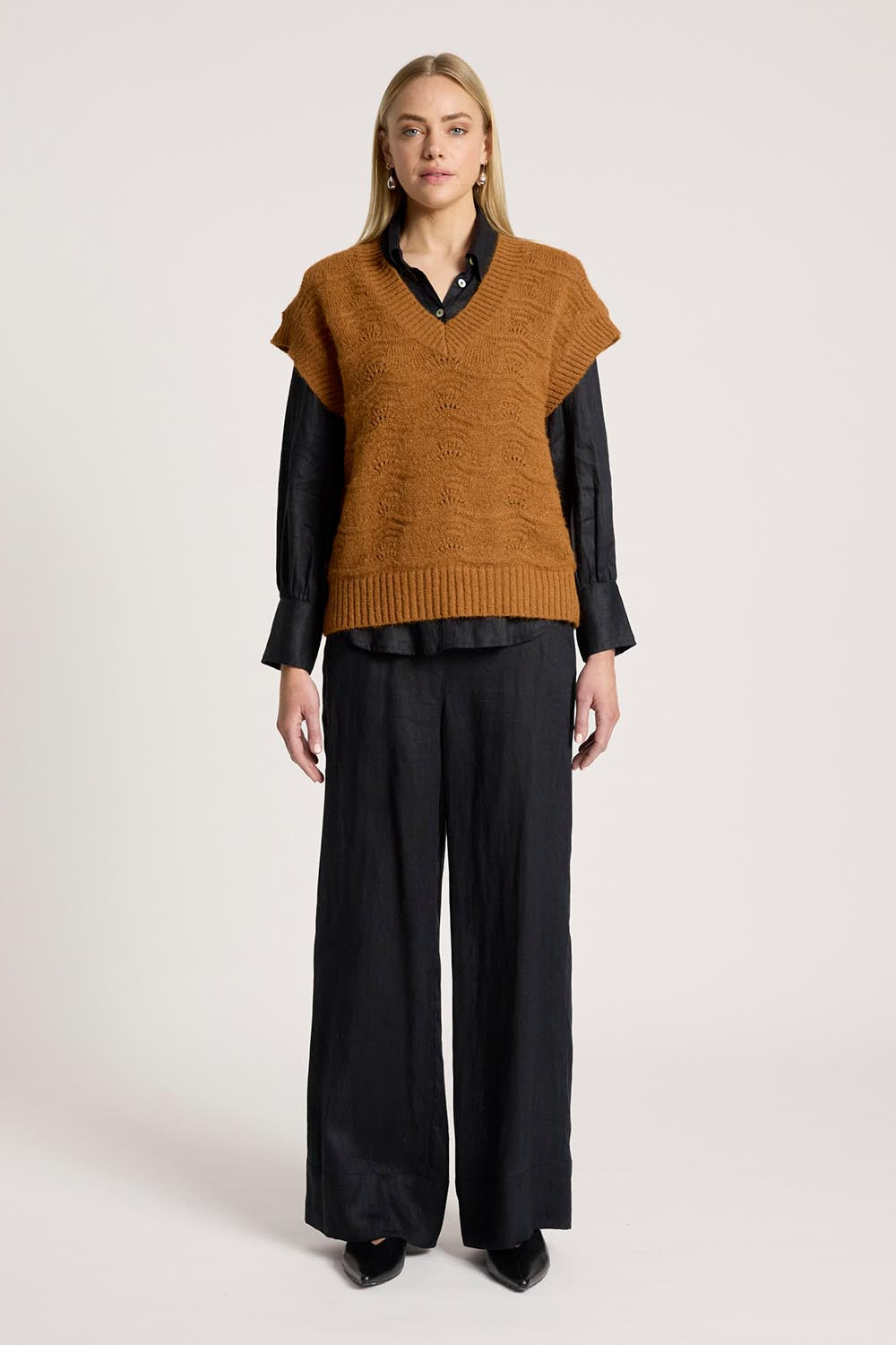 A model wearing the Orin Knit Vest in colour Caramel, from the front, showing the whole outfit
