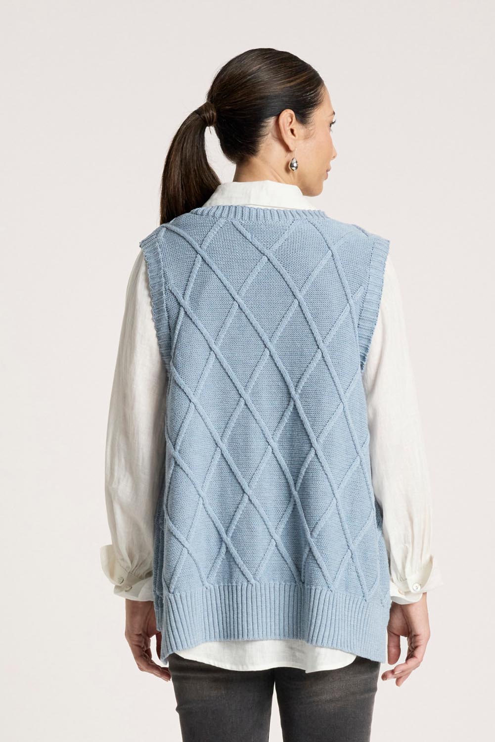 A model wearing the Liora Knit Vest in colour Lake (Blue), from the back