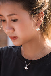 A model wearing the Song Of Freedom Earrings in colour Steel (Metallics), from the front, showing the whole outfit
