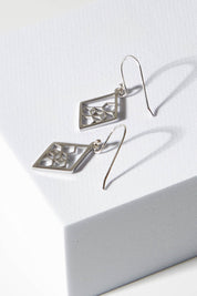 A model wearing size OneSize of the Shielding Hope Earrings in colour Steel (Metallics), from the front, showing the whole outfit