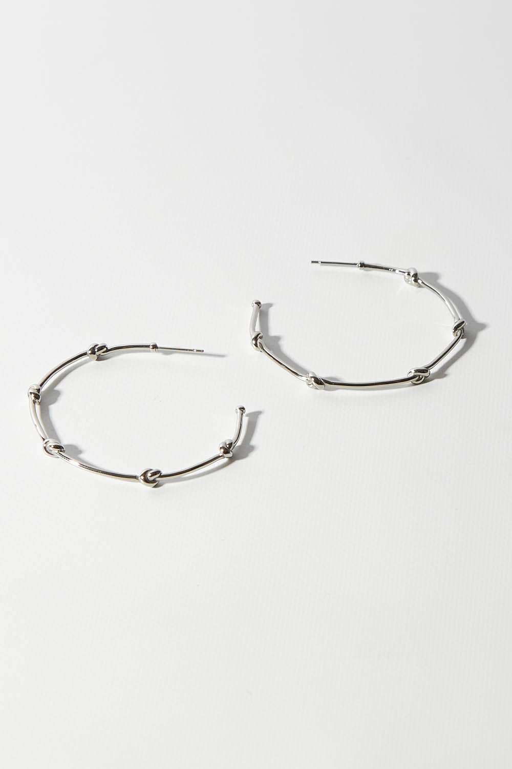 A model wearing size OneSize of the Knots Of Freedom Hoop Earrings in colour Steel (Metallics), from the front, showing the whole outfit