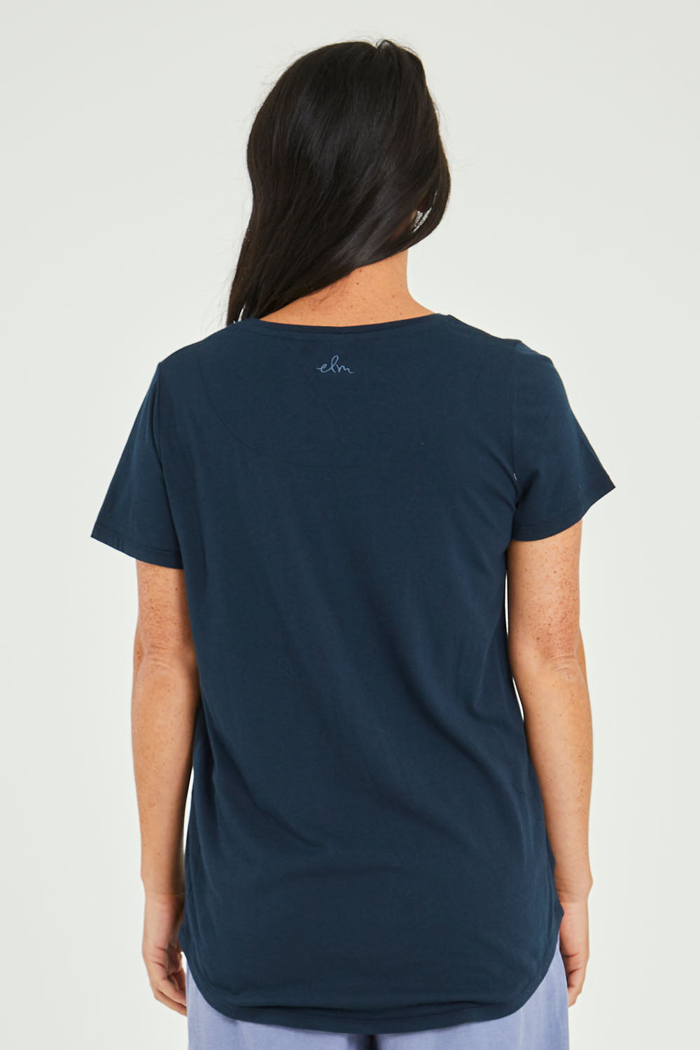Model Katie wearing size 10 of the Ampersand Tee in colour Drksapp (Blue), from the back
