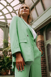 A model wearing the Rhiannon Blazer in colour Meadow (Green), from the front, showing the whole outfit