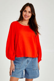Model Madeline wearing size 10 of the Rosa Top in colour Tangello (Red), from the front, cropped image