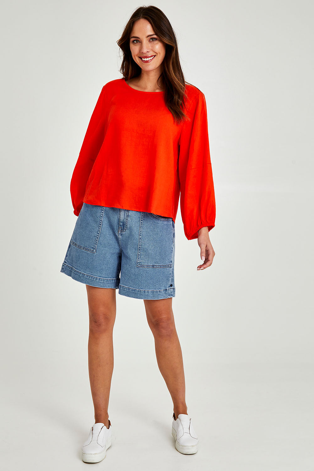Model Madeline wearing size 10 of the Rosa Top in colour Tangello (Red), from the front, showing the whole outfit