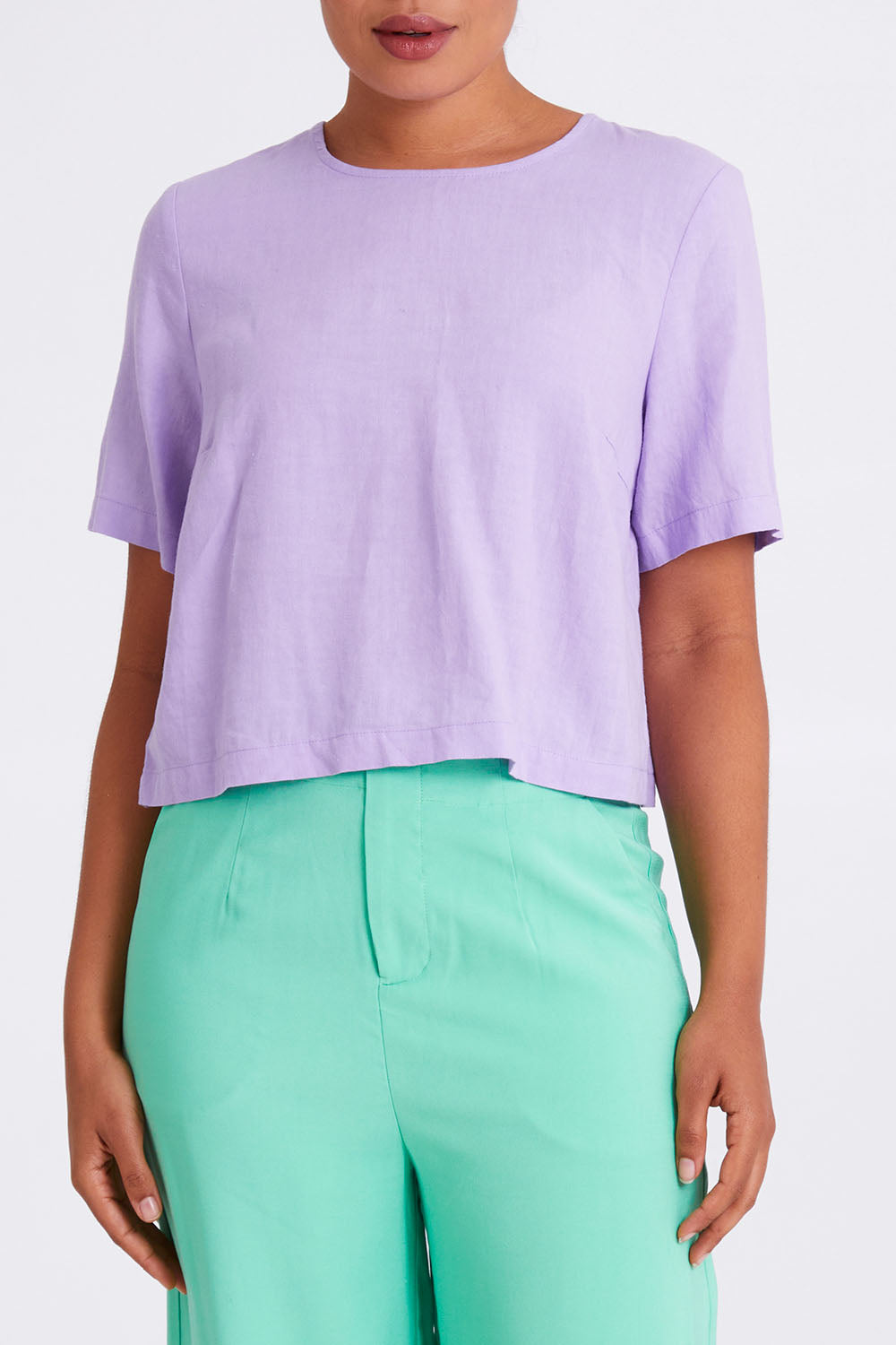 Model Olivia wearing size 10 of the Juniper Top in colour Periwinkle (Purple), from the front, cropped image