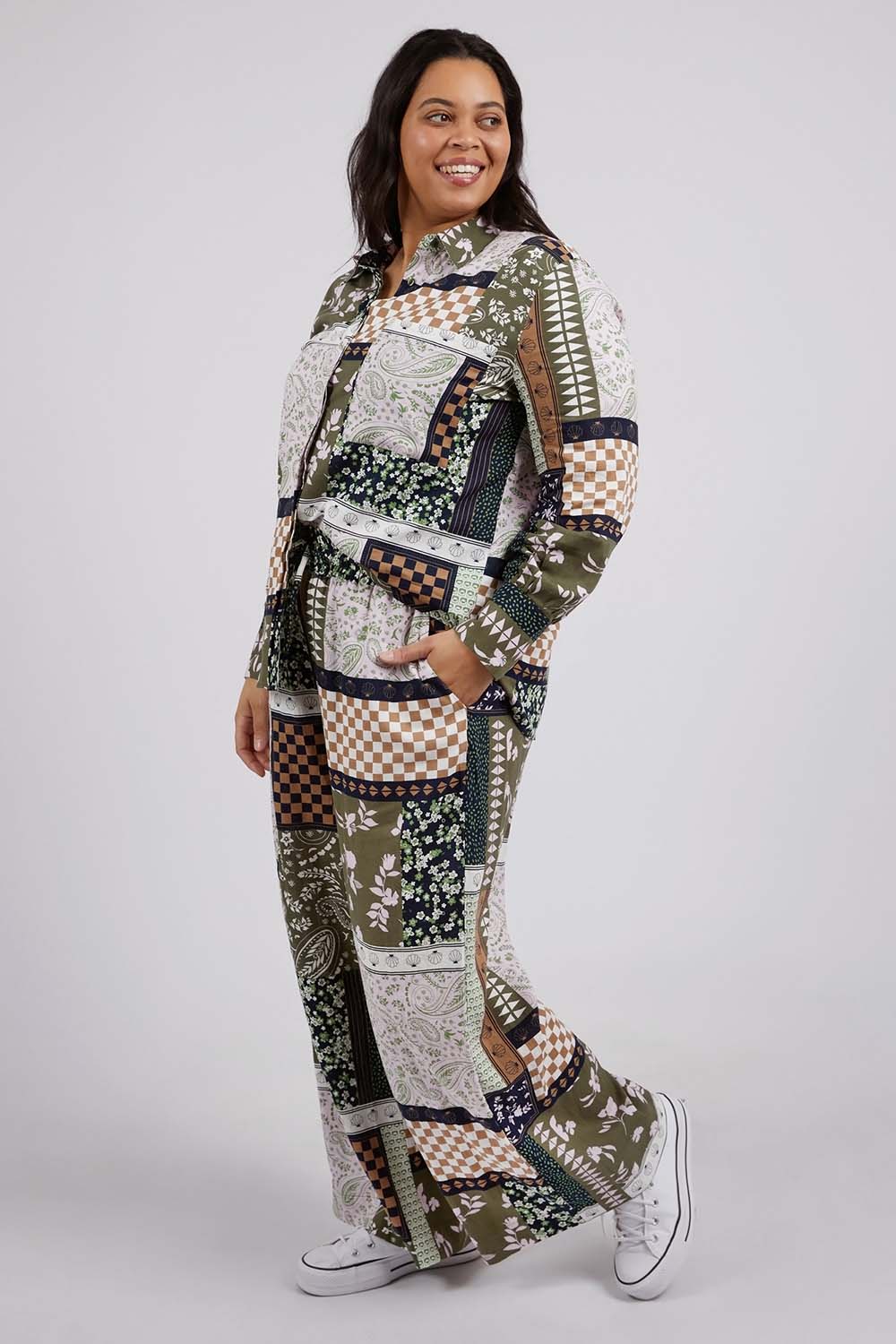 A model wearing the Vetiver Patchwork Shirt in colour Patchwork (Green), from the front, showing the whole outfit