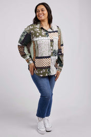 A model wearing the Vetiver Patchwork Shirt in colour Patchwork (Green), from the front, showing the whole outfit