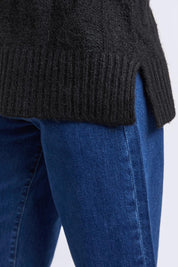 A model wearing the Tallulah Cable Knit in colour Black (Black), from the front, cropped image