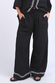 A model wearing the Nina Embroidered Pant in colour Black (Black), from the front, cropped image