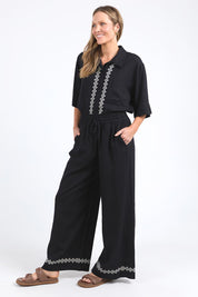 A model wearing the Nina Embroidered Pant in colour Black (Black), from the front, showing the whole outfit