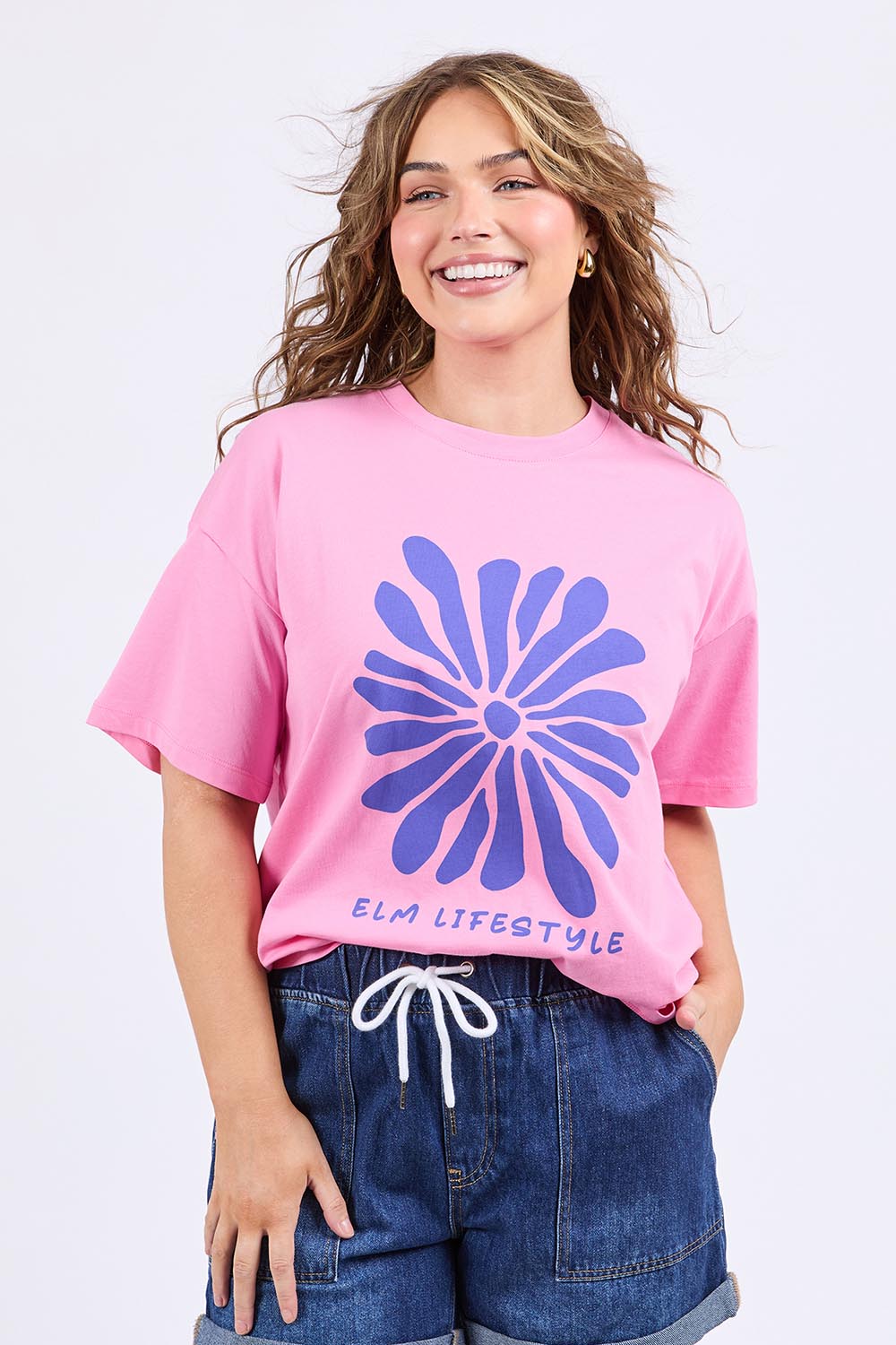 A model wearing the Camelia Cotton Tee in colour Chateauros (Pink), from the front, cropped image