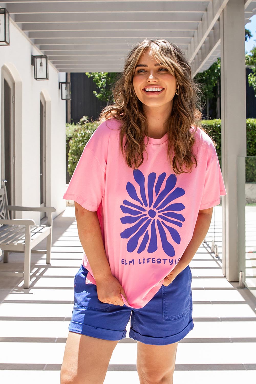A model wearing the Camelia Cotton Tee in colour Chateauros (Pink), from the front, showing the whole outfit