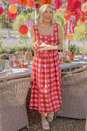 A model wearing the Edin Cotton Dress in colour Poppycheck, from the front, showing the whole outfit