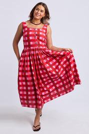 A model wearing the Edin Cotton Dress in colour Poppycheck, from the front, showing the whole outfit