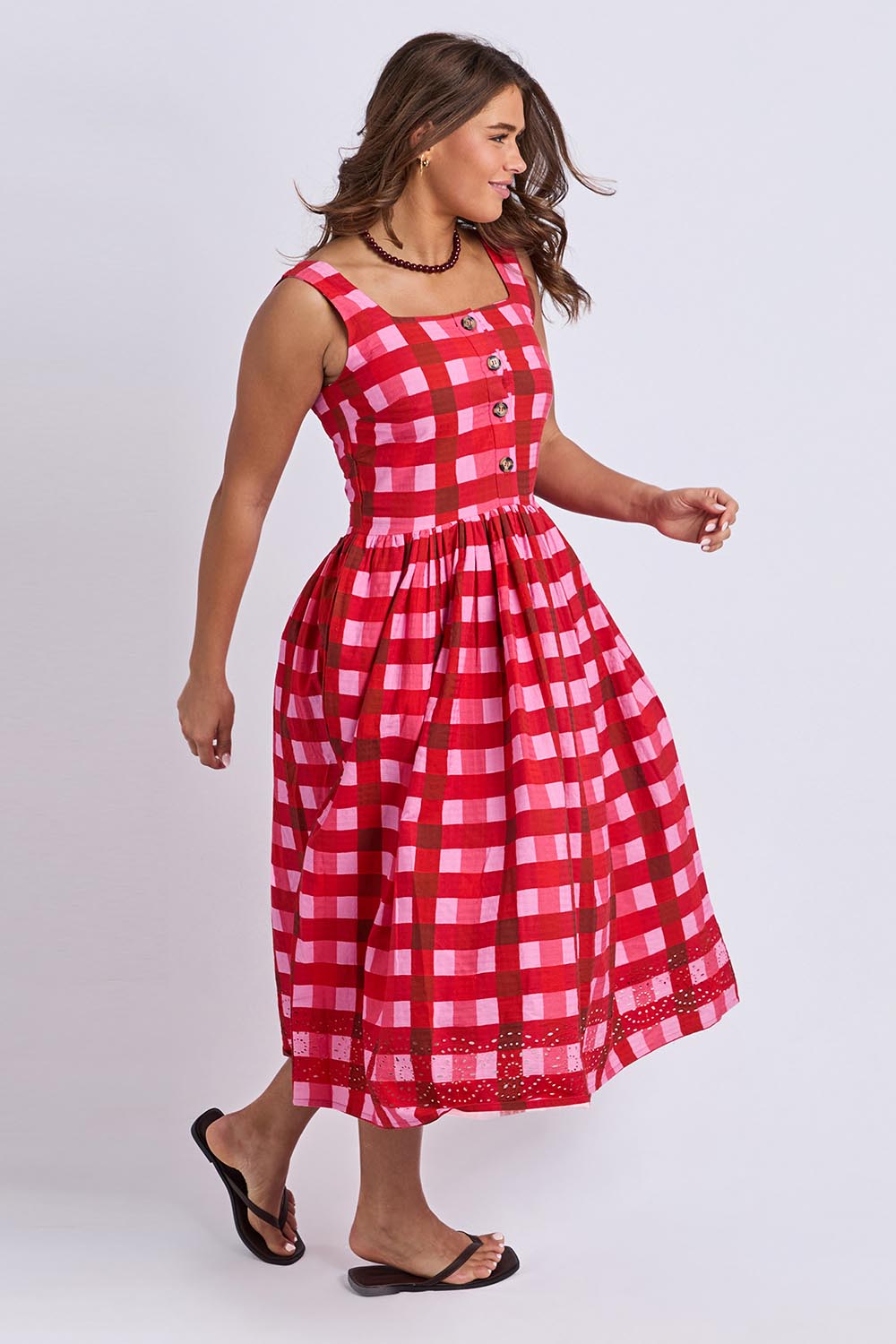 A model wearing the Edin Cotton Dress in colour Poppycheck, from the front, showing the whole outfit