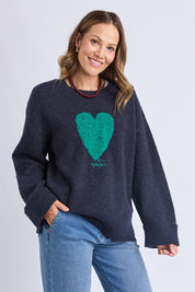 A model wearing the Intersia Heart Knit in colour Navy (Blue), from the front, cropped image