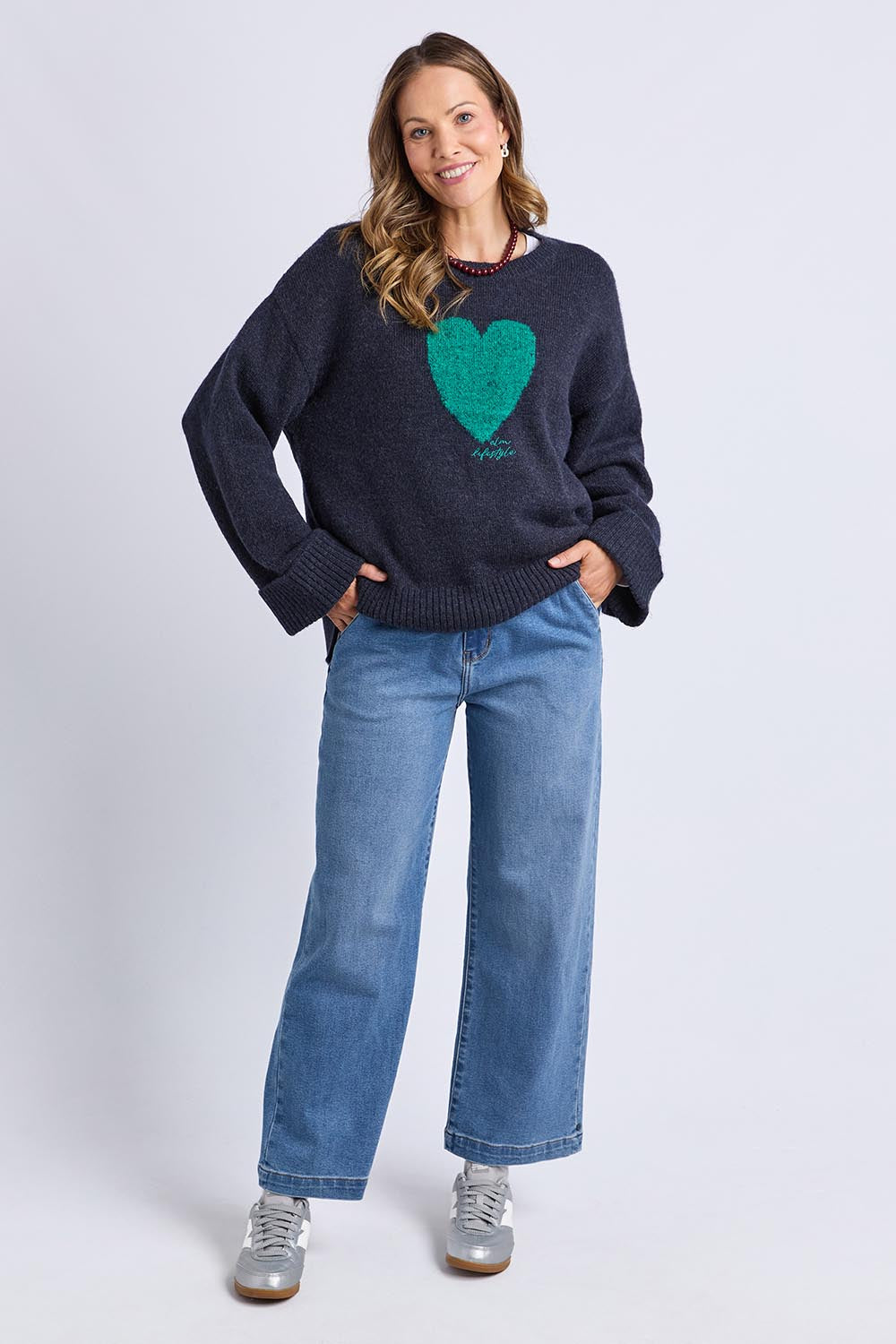 A model wearing the Intersia Heart Knit in colour Navy (Blue), from the front, showing the whole outfit
