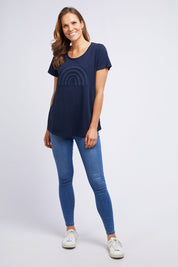 A model wearing the Crescent SS Tee in colour Navy (Green), from the front, showing the whole outfit