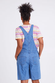 Model Olivia wearing size 10 of the Maltilda Short Denim Overalls in colour Midblue (Blue), from the back