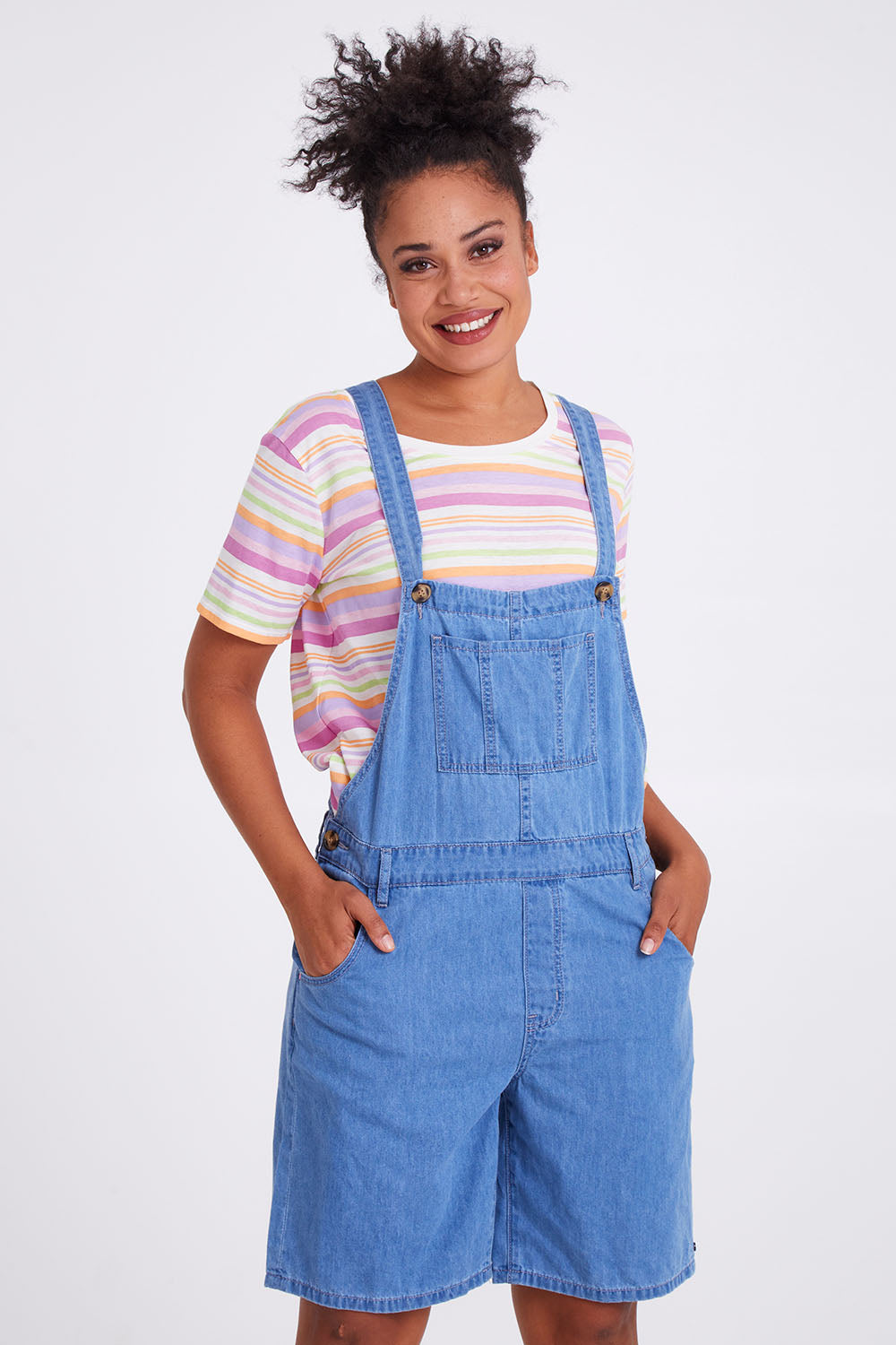 Model Olivia wearing size 10 of the Maltilda Short Denim Overalls in colour Midblue (Blue), from the front, cropped image