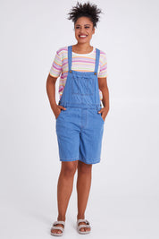 Model Olivia wearing size 10 of the Maltilda Short Denim Overalls in colour Midblue (Blue), from the front, showing the whole outfit